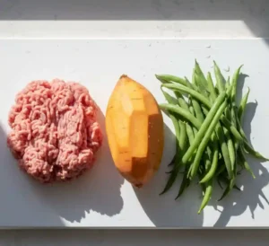 Fresh ingredients for homemade dog food including lean turkey, sweet potatoes, and green beans.